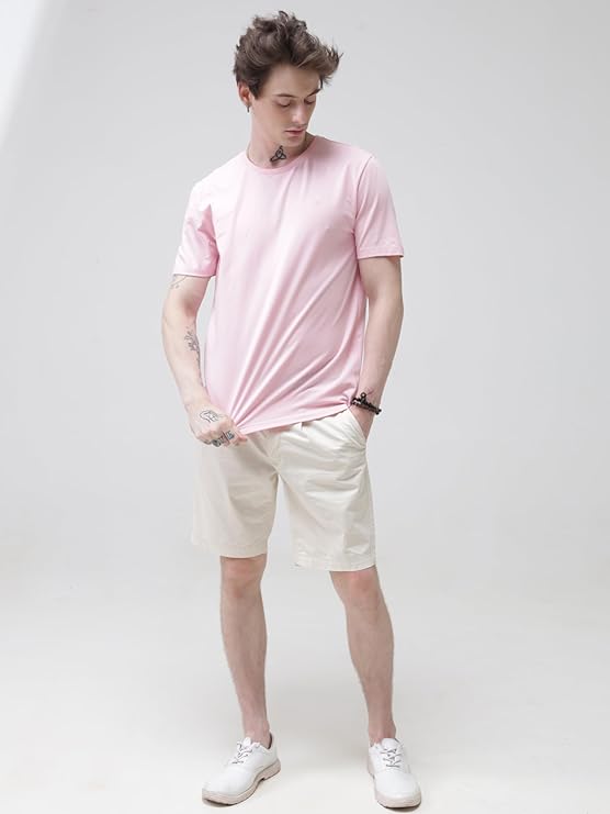 Person wearing a pink t-shirt and beige shorts on a white background