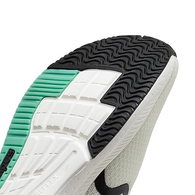 Close-up of a shoe sole with green, white, and black tread pattern on a white background