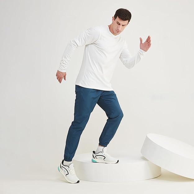 Man wearing a white long-sleeve shirt, blue pants, and white sneakers on a white background