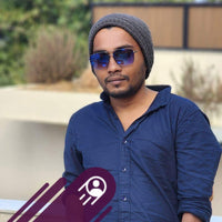 Man wearing a blue shirt, gray beanie, and sunglasses outdoors