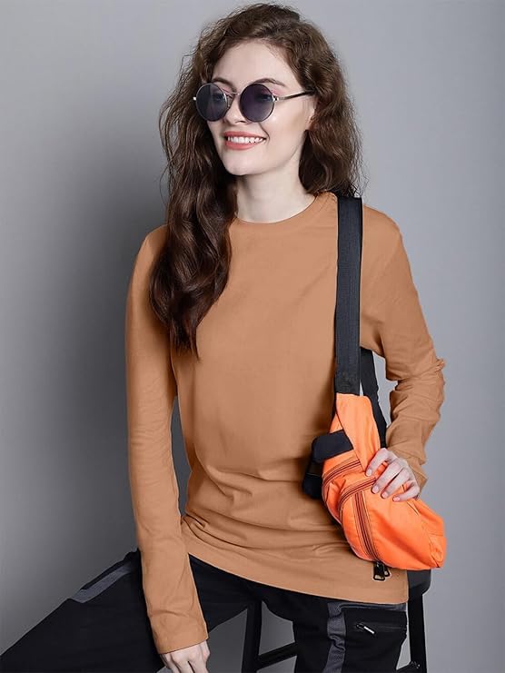 Woman wearing a brown long-sleeve top and sunglasses, holding an orange bag against a gray background