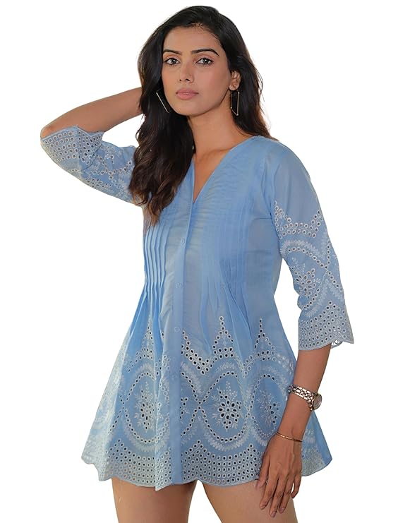 Woman wearing a light blue embroidered dress on a white background