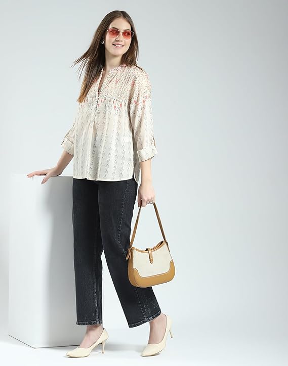 Woman wearing a beige blouse and black jeans, holding a yellow handbag on a white background