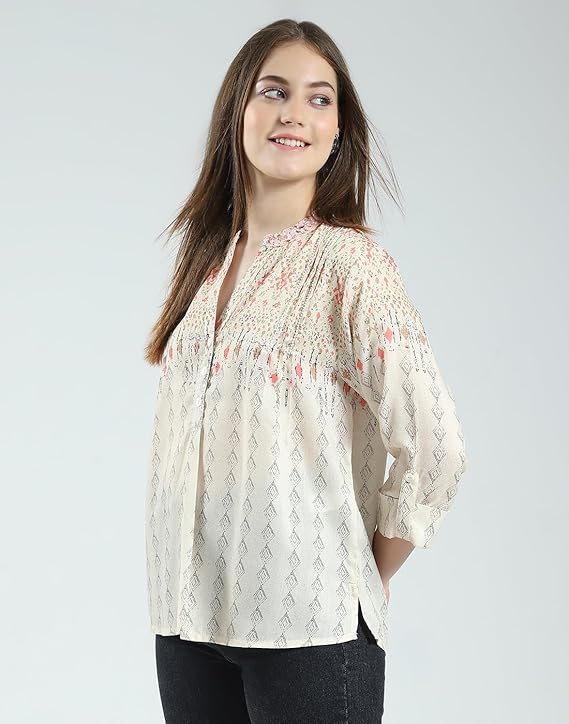 Woman wearing a white blouse with floral patterns on a plain background